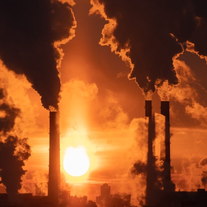 Winter industrial landscape. Coal-fired power station with smoking chimneys against dramatic sunset sky. Air pollution in city. Carbon dioxide CO2 emissions as primary driver of global climate change