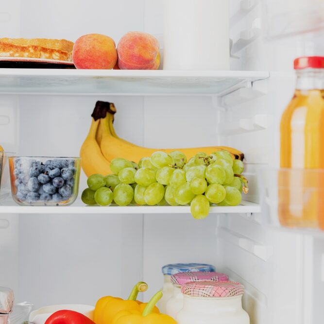 Front View of open two door fridge or refrigerator door filled with fresh fruits, vegetables, juice, full of healthy food items and ingredients inside. Electric Kitchen and Domestic Major Appliances