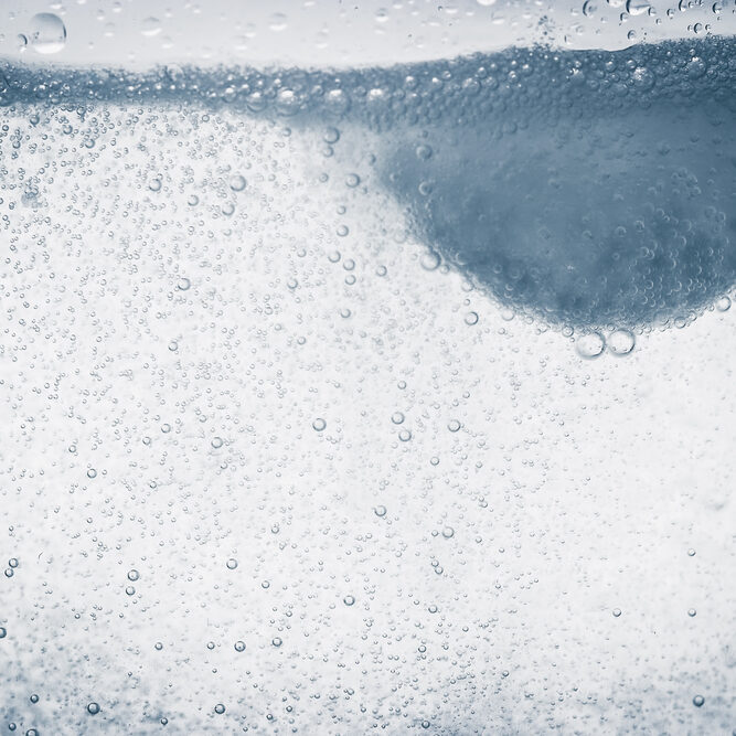 A soluble tablet dropped in a glass of water over white background Toned